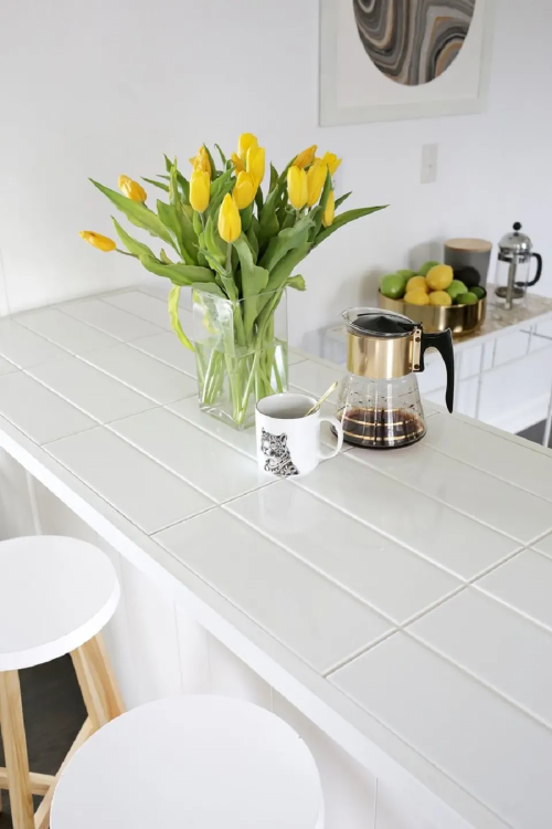 white tiled countertop in kitchen with yellow tulips